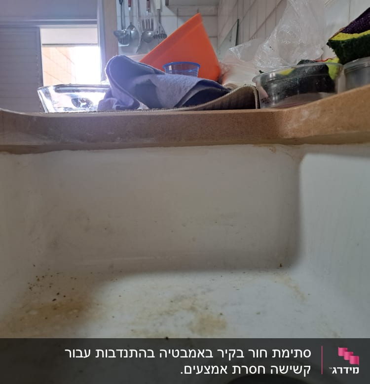 כיור מלוכלך עם כלים וספוגים על השיש